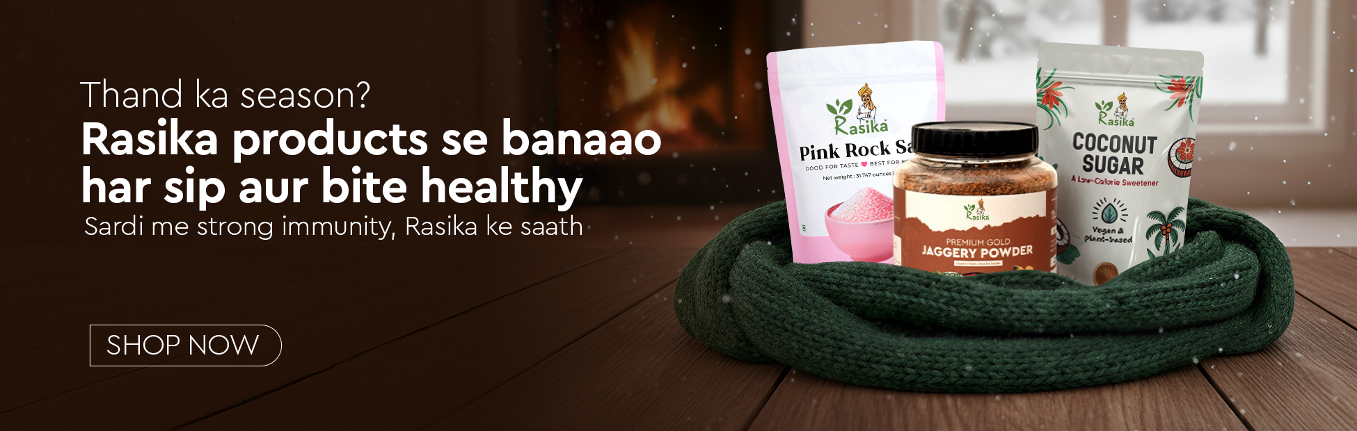 Rasika products including a jar and packets on a wooden surface with a fireplace in the background.